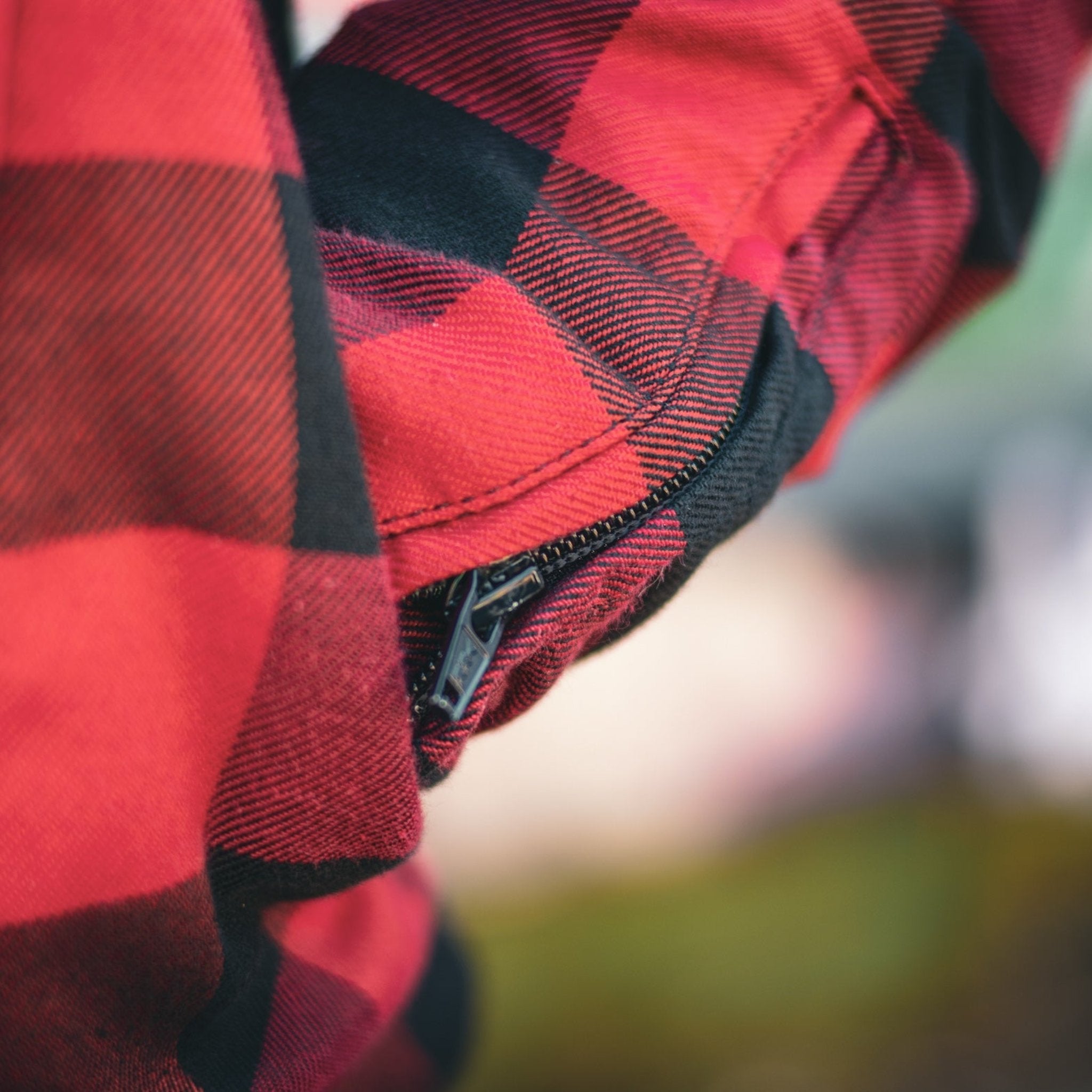 close up of sleeve with zipper detail on red and black flannel-style women's jacket from moto girl