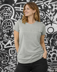 Woman wearing a gray t-shirt with 'Motocross Girl' text against a graffiti-covered wall.
