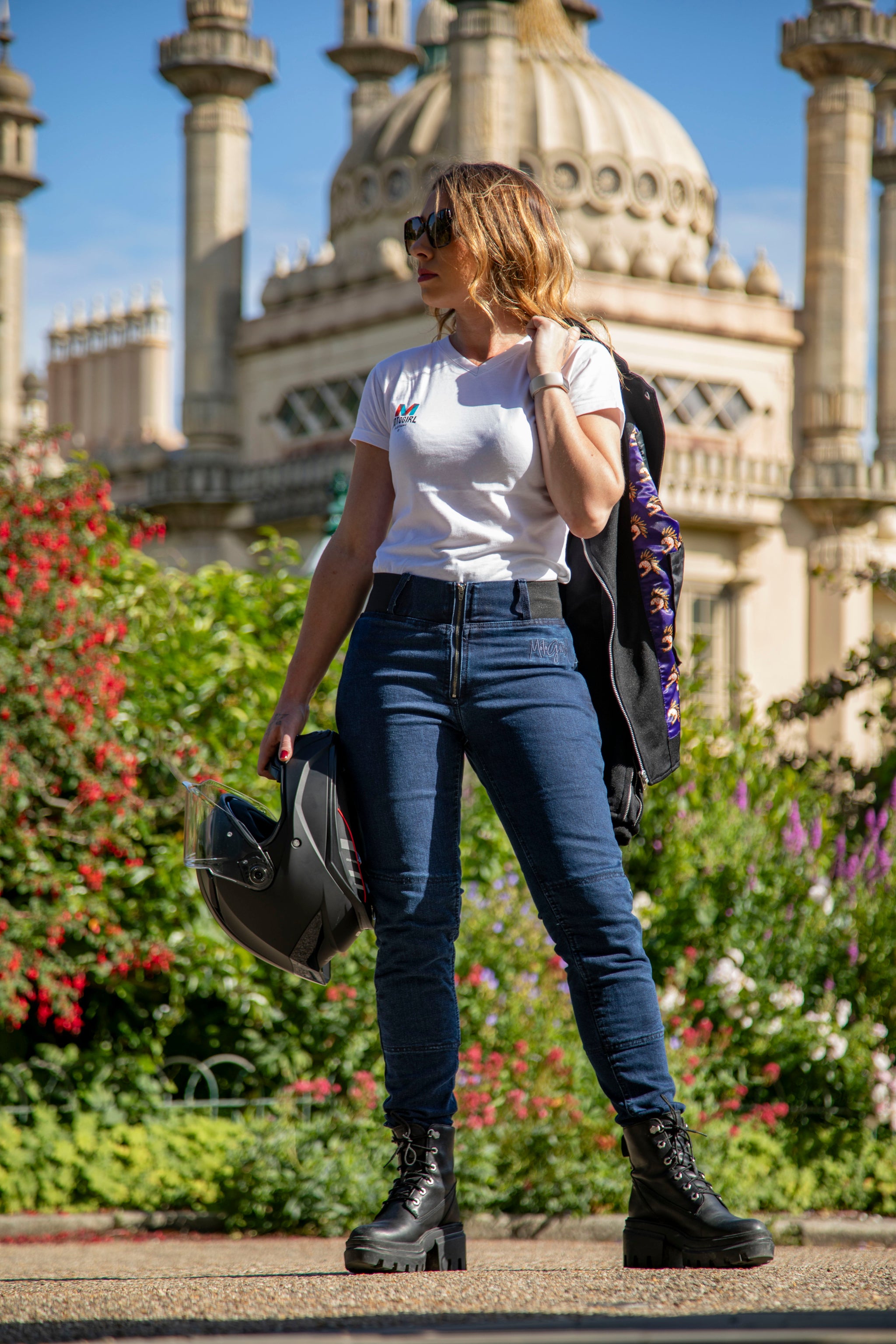 young woman wearing white t-shirt and blue jeans and holding motorcycle helmet