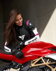 Young woman wearing black, white, pink SHIMA motorcycle  leather suit with her red motorcycle