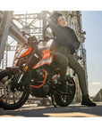 a woman on an orange motorcycle wearing black shirt looking lady motorcycle jacket
