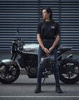 A young woman standing by her motorcycle wearing blue motorcycle jeans