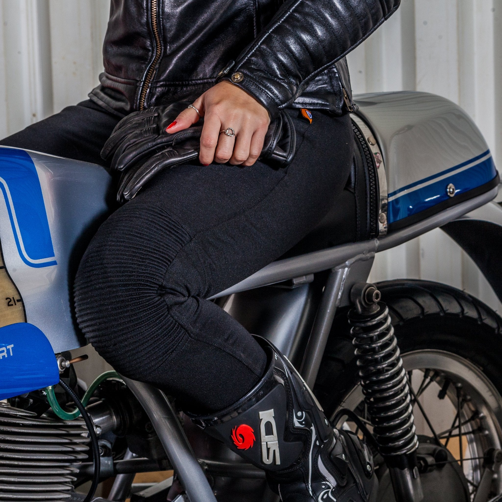 Half body of a woman siting on a motorcycle wearing black lady motorcycle leggings from MotoGirl