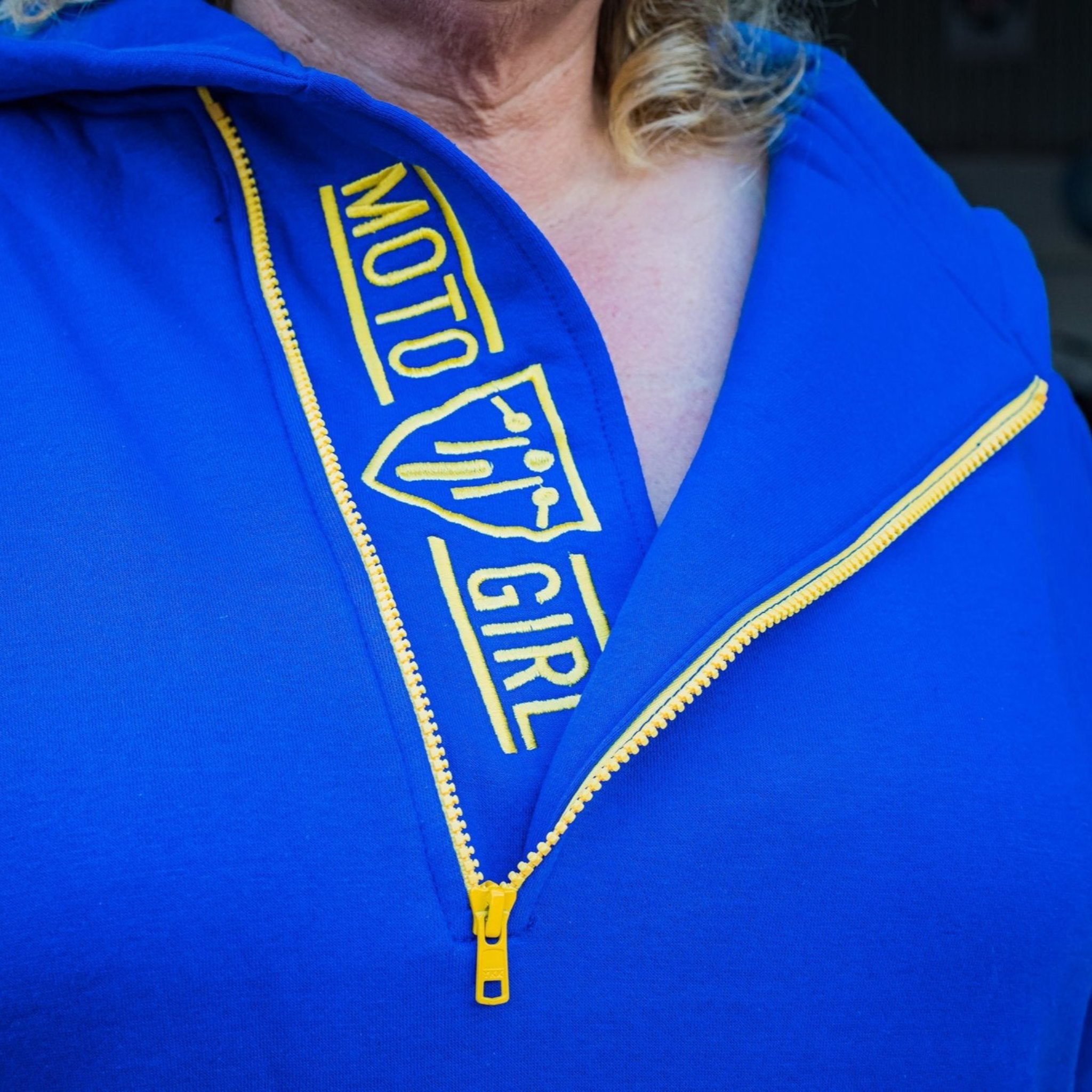 A blond woman wearing blue and yellow motorcycle hoodie