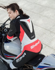 A woman on a motorcycle wearing Women's racing suit MIURA RS in black, white and fluo from Shima