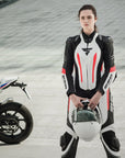 A young woman standing near a motorcycle wearing Women's racing suit MIURA RS in black, white and fluo from Shima