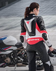 A woman standing near her motorcycle wearing Women's racing suit MIURA RS in black, white and fluo from Shima