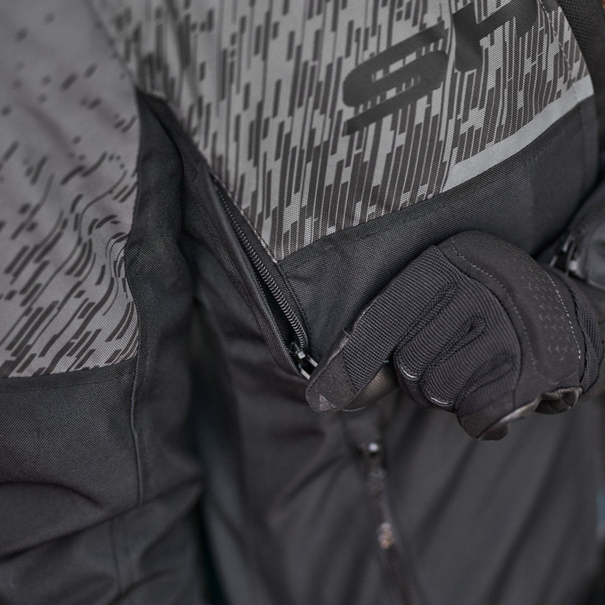 a hand unzipping the ventilation panel on the grey women's motorcycle jacket from SHIMA