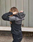 A woman putting a hood of a grey motorcycle jacket  from shima