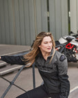 A blond woman near the motorcycle wearing grey women's motorcycle jacket from SHIMA