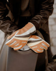 women's hands over a motorcycle gas tank wearing colourful leather gloves from WILDUST