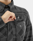 Person wearing a black checkered jacket with a close-up of a pocket.