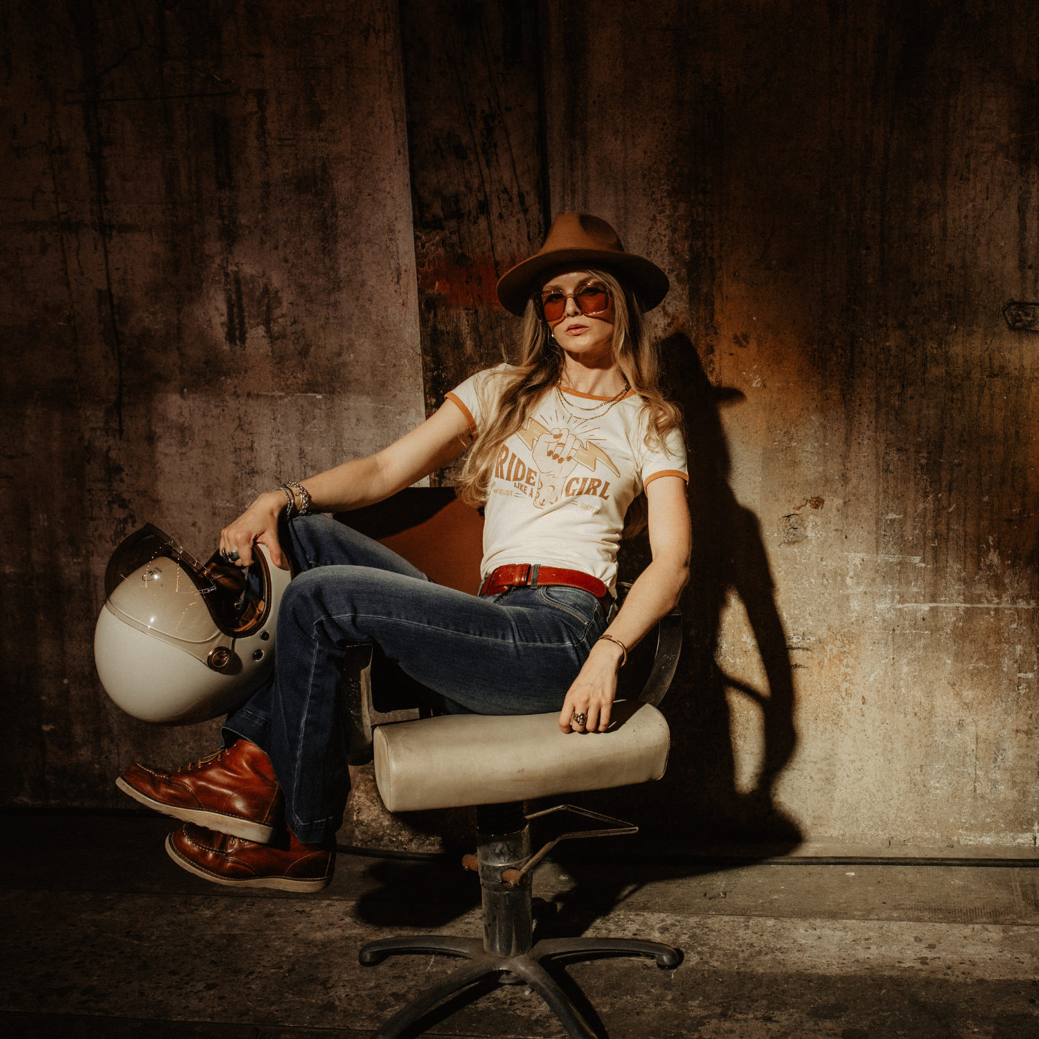 A woman sitting on a chair, wearing RIDE LIKE A GIRL retro style women's t-shirt from Wildust Sisters