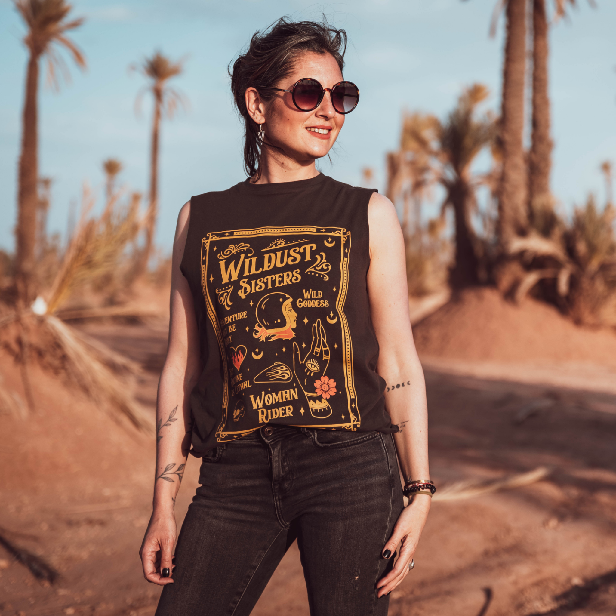 Woman wearing black t-shirt with a woman wearing a Motorcycle helmet with the text "Wildust sister" 