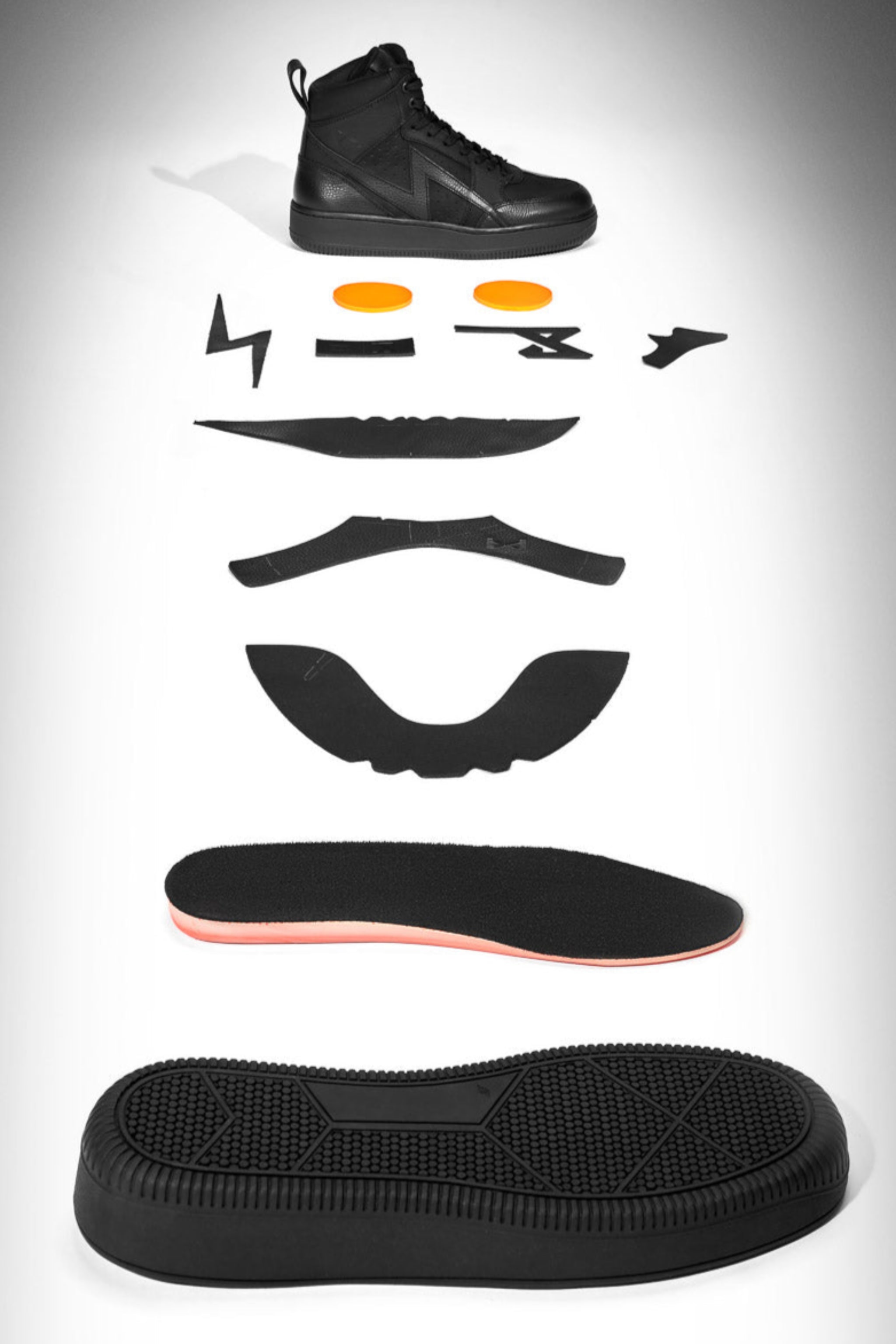 Black sneaker disassembled into its components on a gray background