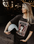 Woman with a Motorcycle helmet wearing a T-shirt with a women wearing a Motorcyclehelmet print and with the text "Wild dust sisters woman rider" and "Speed Goddess"