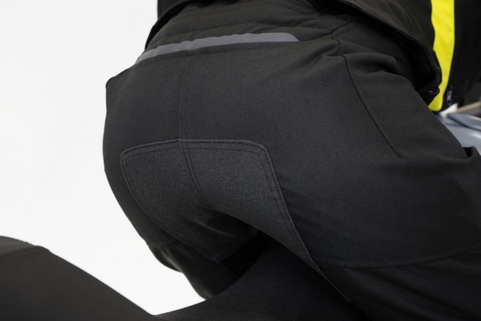 Woman&#39;s bottom wearing black textile motorcycle pants with non-slide patch  