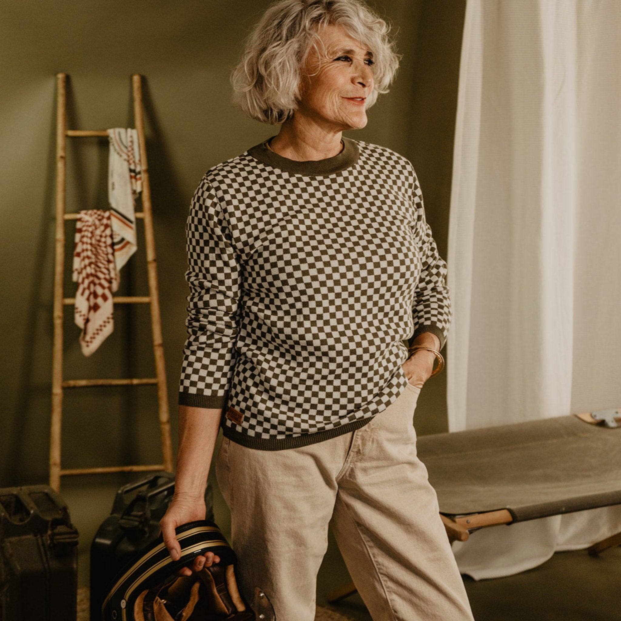 an older lady wearing a knitted khaki green and white jumper with chessboard motives  from Wildust