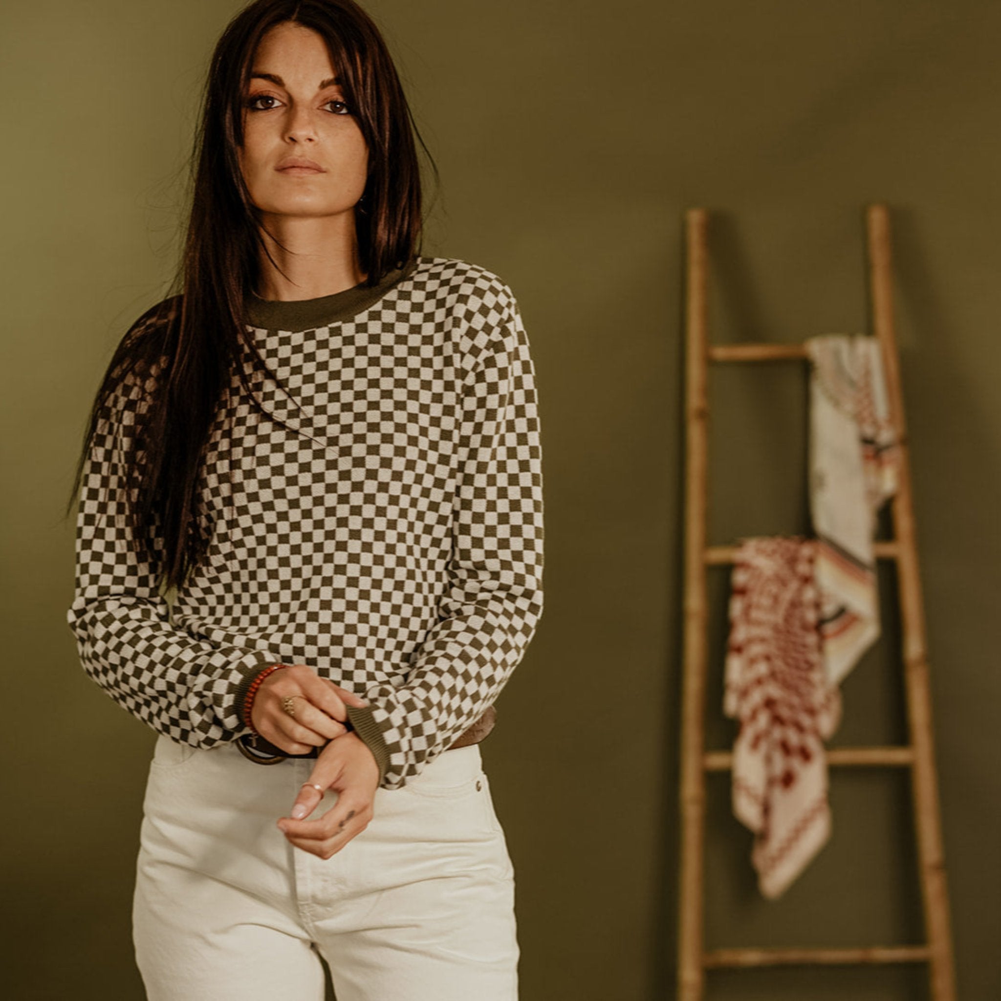 a young woman wearing  a knitted khaki green and white jumper with chessboard motives from Wildust