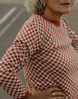 an older lady wearing a knitted red and white jumper with chessboard motives from Wildust