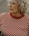 an older lady wearing a knitted red and white jumper with chessboard motives from Wildust