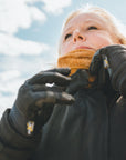 blond woman standing outside while wearing a caramel color knitted neck warmer from Moto Girl. 