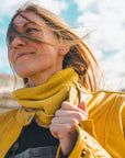 Woman standing outside wearing a yellow Valerie jacket and a yellow knitted neck warmer from Moto Girl.