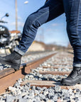 Woman's legs standing on the railway and wearing black motorcycle boots