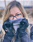 light haired woman in motorcycle gear, wearing a light gray neck warmer from Moto Girl outside, showing the inner lining of the neck warmer.