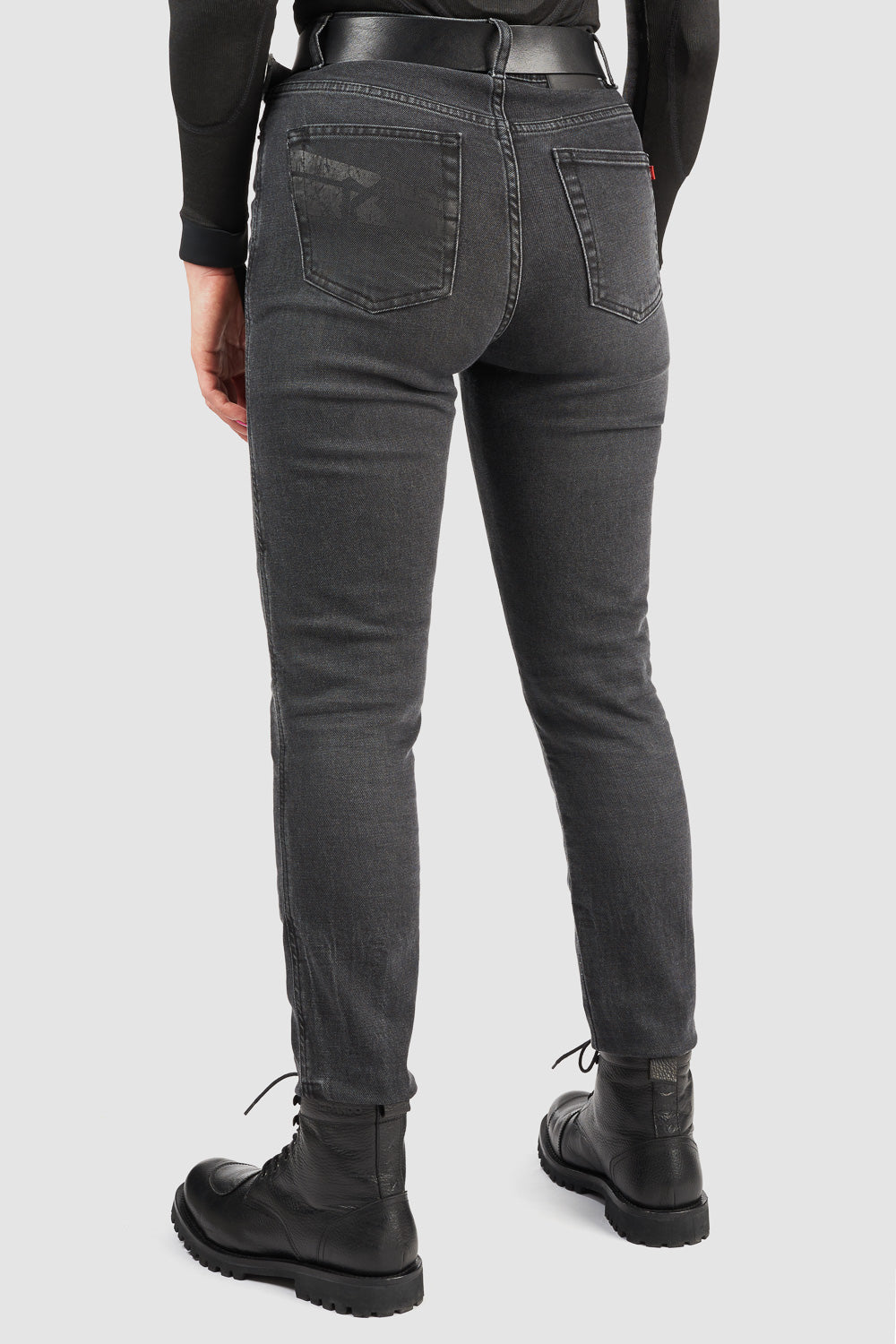 Person wearing black jeans from behind on a light gray background