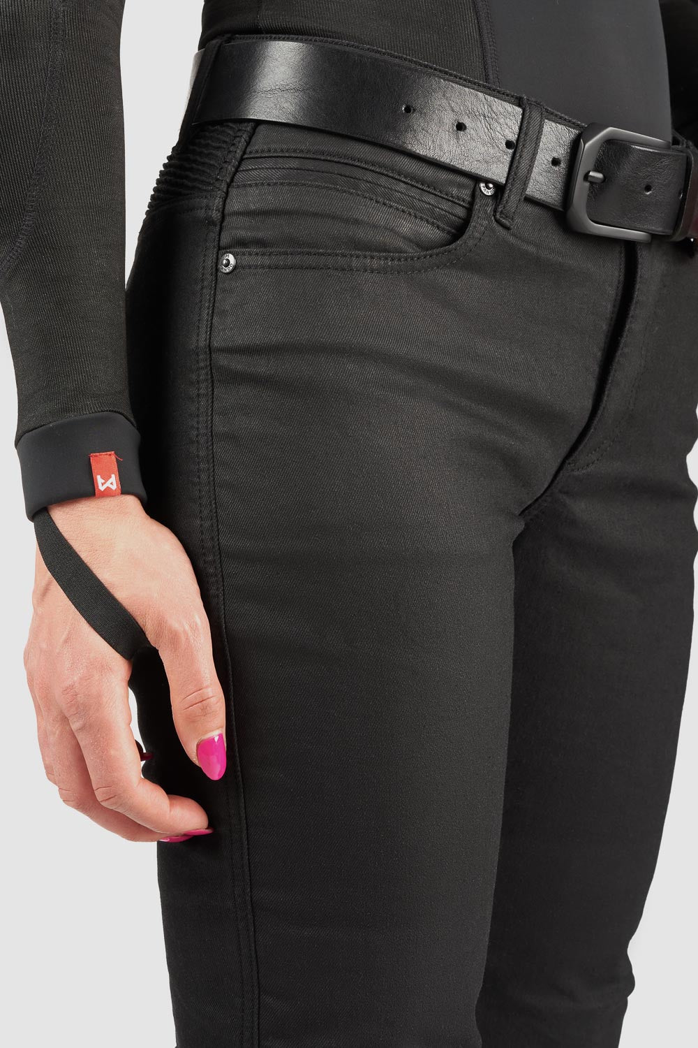 Person wearing black mc pants with a belt, holding a black strap against a white background