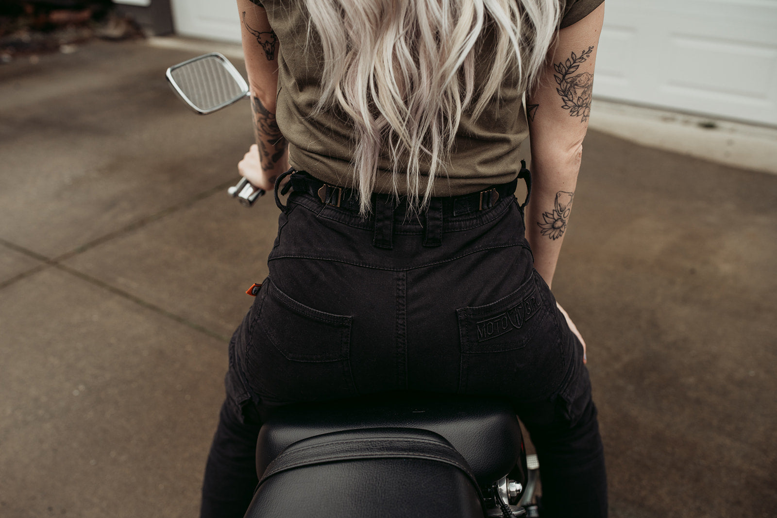 a back of a woman siting on a motorcycle wearing adjustable waist black mc pants 