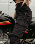 Half body of a woman siting on a motorcycle and wearing black motorcycle cargo pants from moto girl with big pockets s