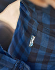 Close-up of a blue plaid shirt with a visible brand logo.