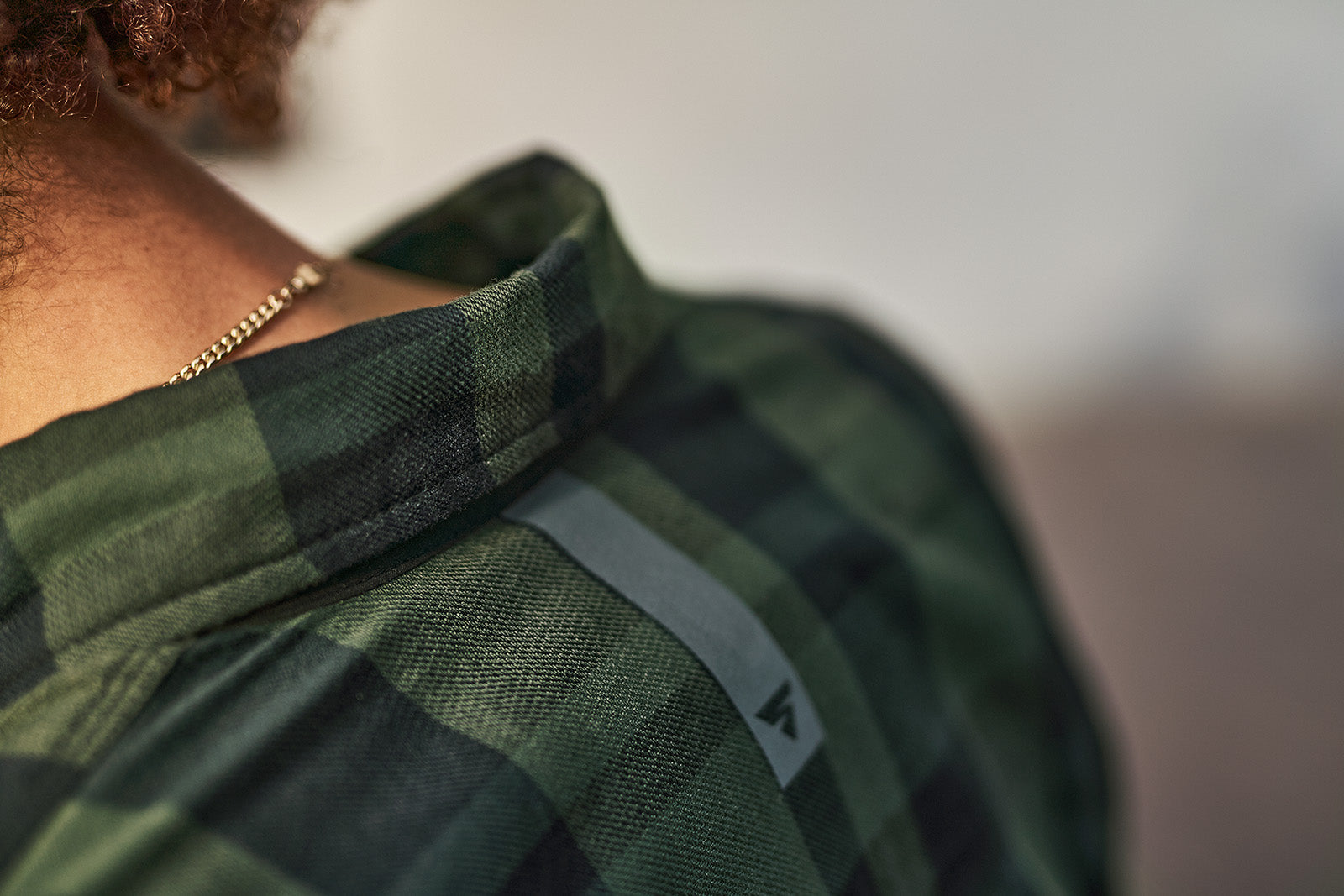 Green plaid shirt with a brand logo on a blurred background