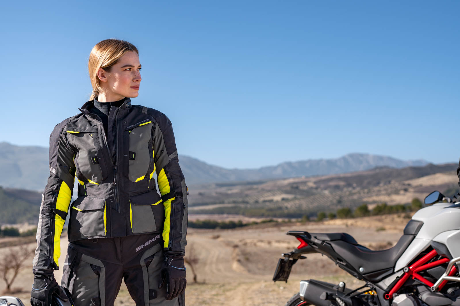 a. woman standing by her motorcycle wearing black fluo motorcycle lady jacket