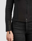 Person wearing a black jacket with textured panels on a white background