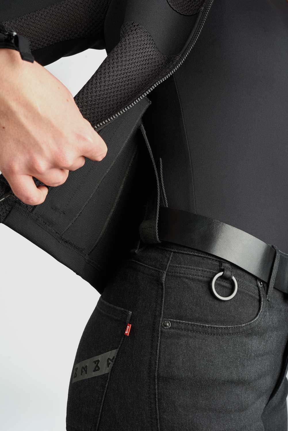 Person wearing a black jacket and pants with a visible brand logo on a white background