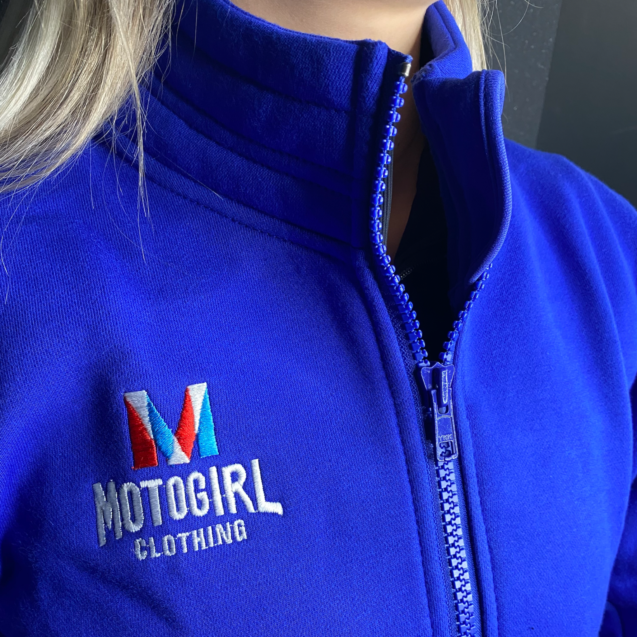 close up of woman's neck wearing Motogirl clothing blue sweatshirt with a front zip