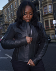 a black woman wearing black leather motorcycle jacket and zipping it in front