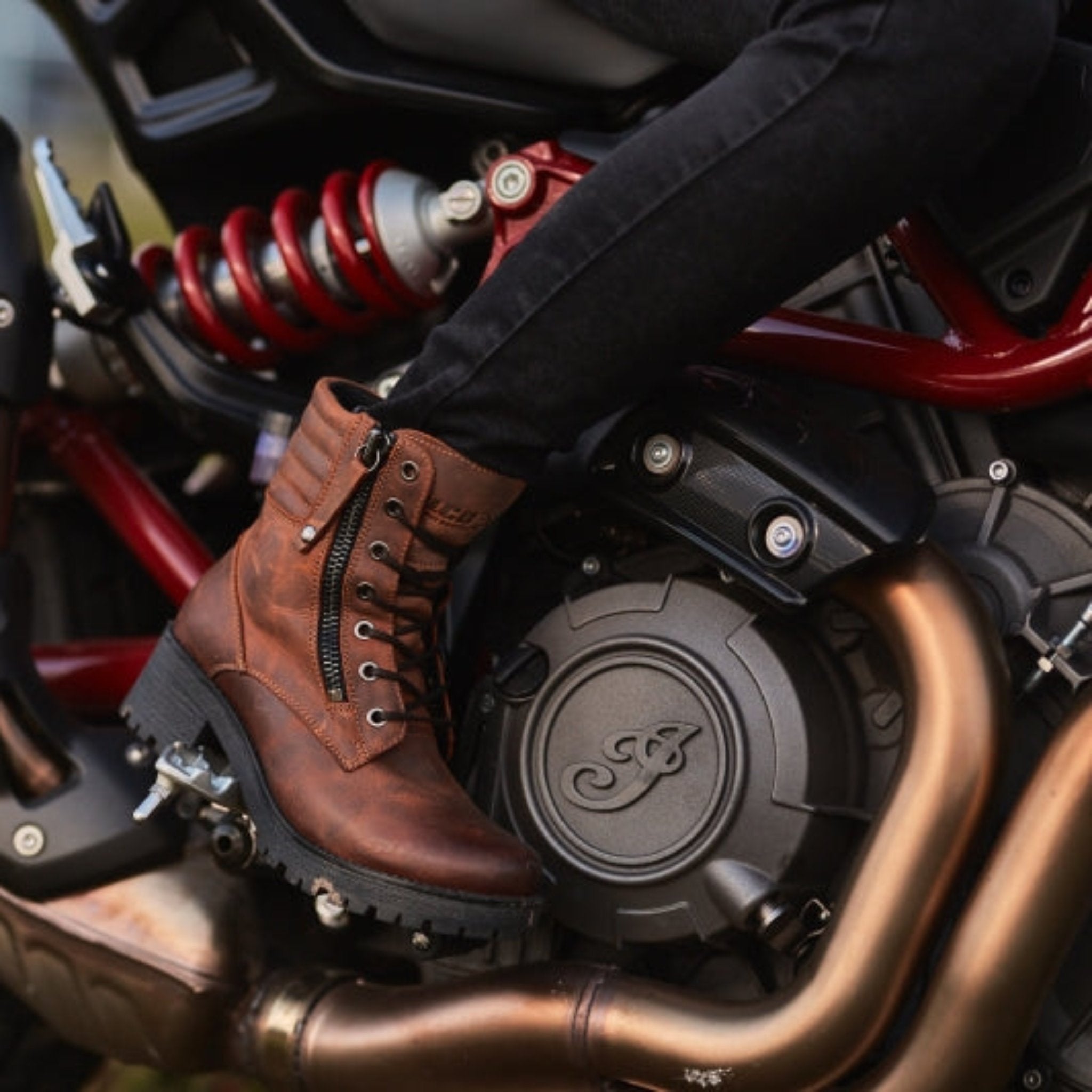 woman&#39;s foot on a motorcycle rest wearing brown leather mc boots 