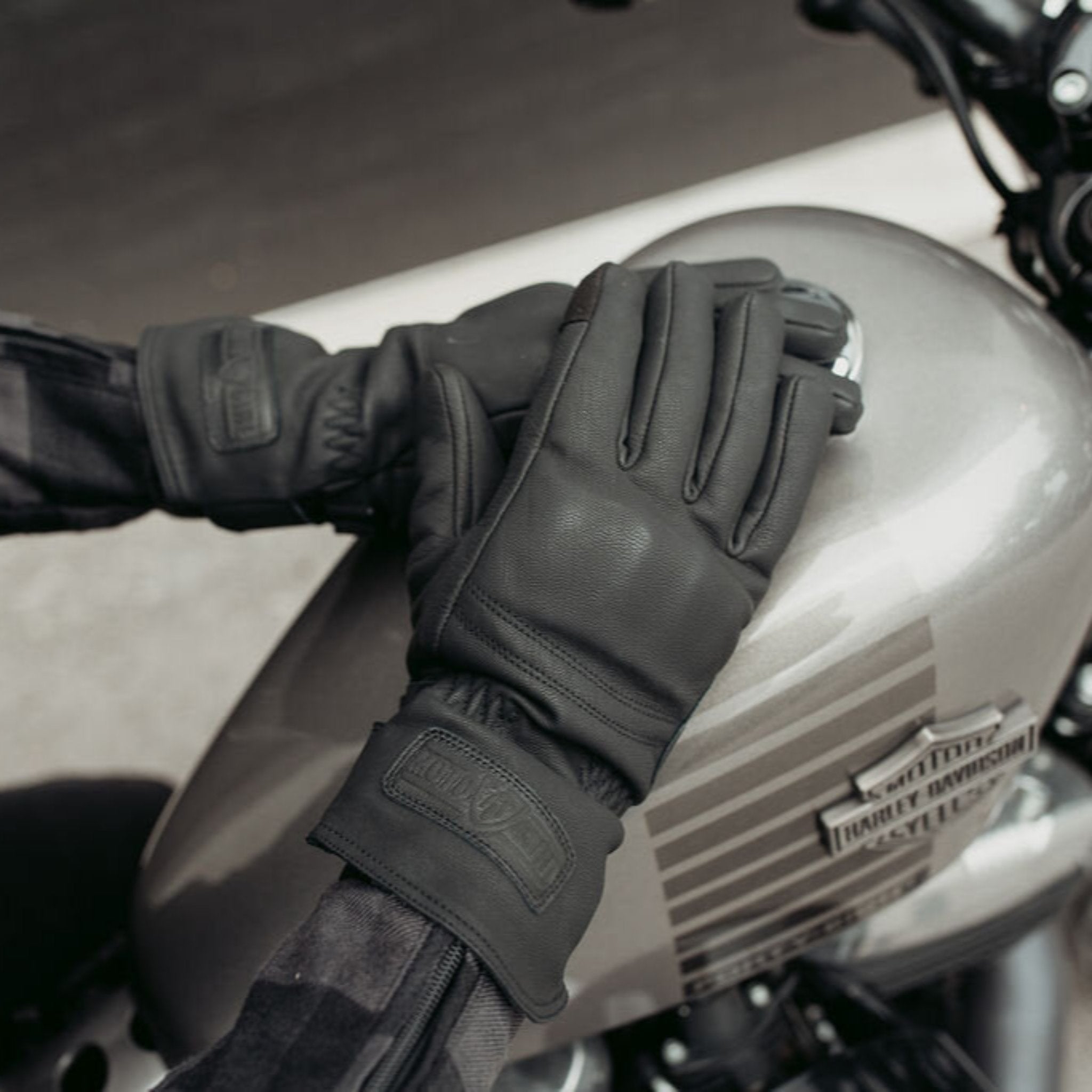 A woman on a Harley Davidson motorcycle wearing black Nandi winter motorcycle gloves from Motogirl.