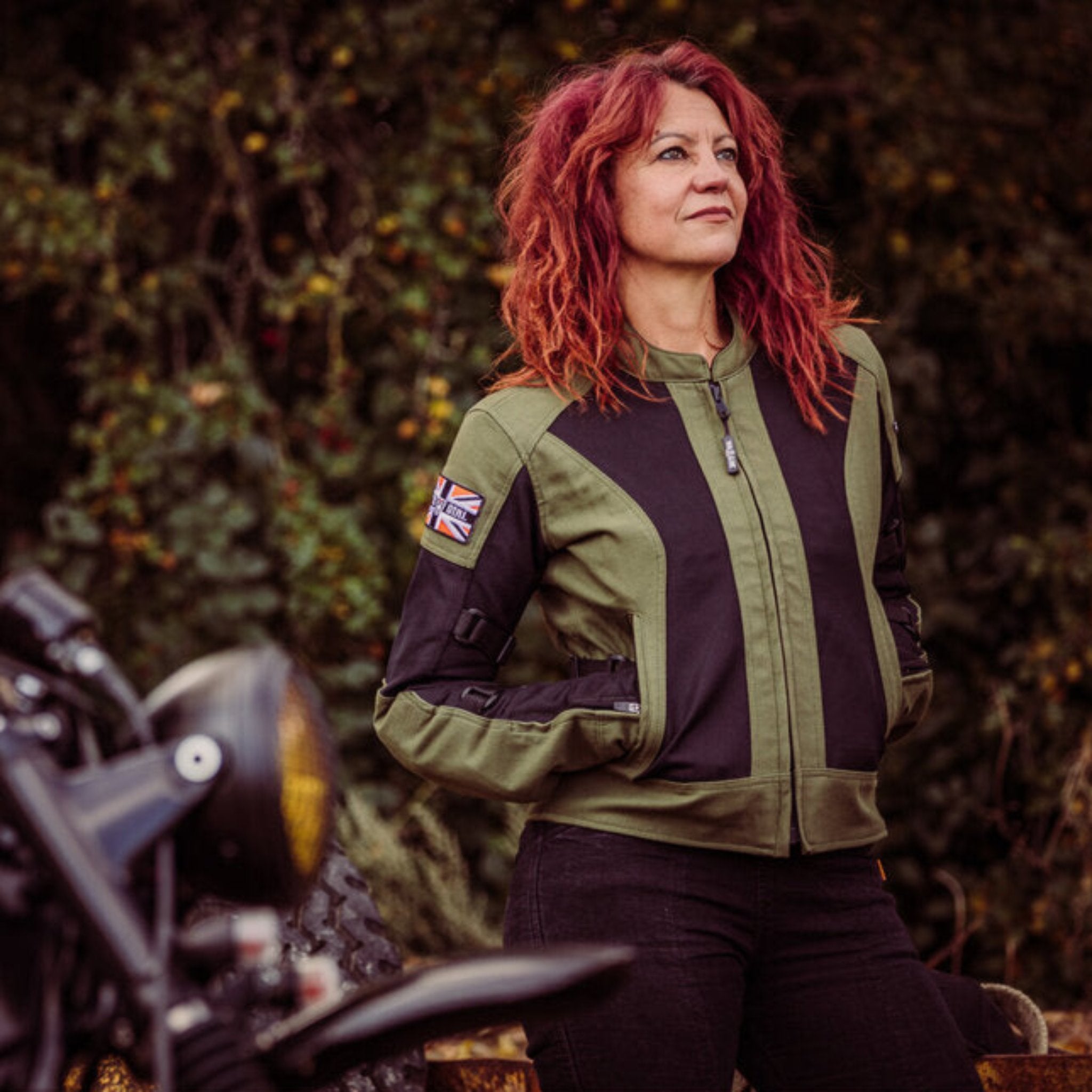 A women standing in front of a motorcycle wearing Women's motorcycle summer mesh jacket in black and green from Moto Girl