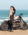 A woman by the beach with her motorcycle wearing Black women's motorcycle overall from Moto Girl 