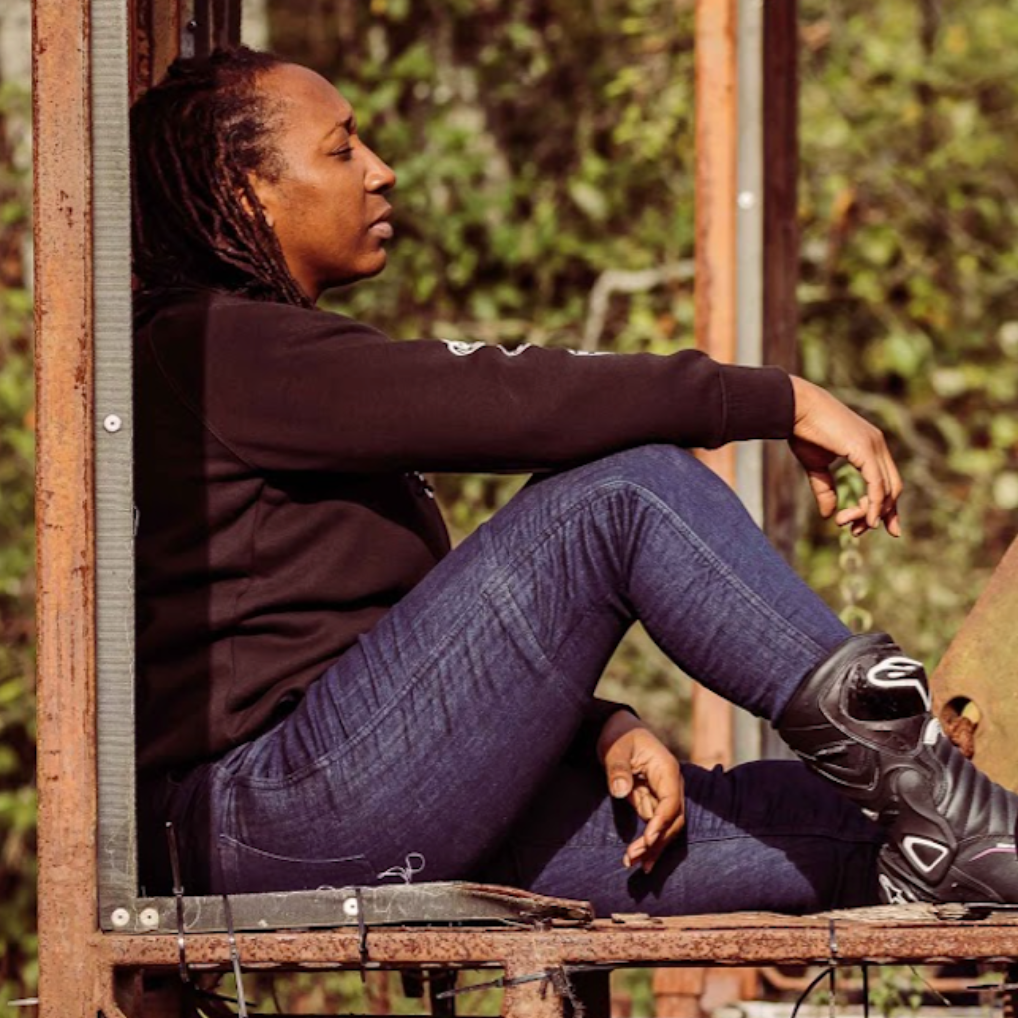 A woman sitting outside while wearing blue motorcycle jeans 