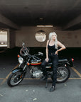 A tattooed woman on her Suzuki motorcycle wearing black lady motorcycle jeans from Moto Girl.