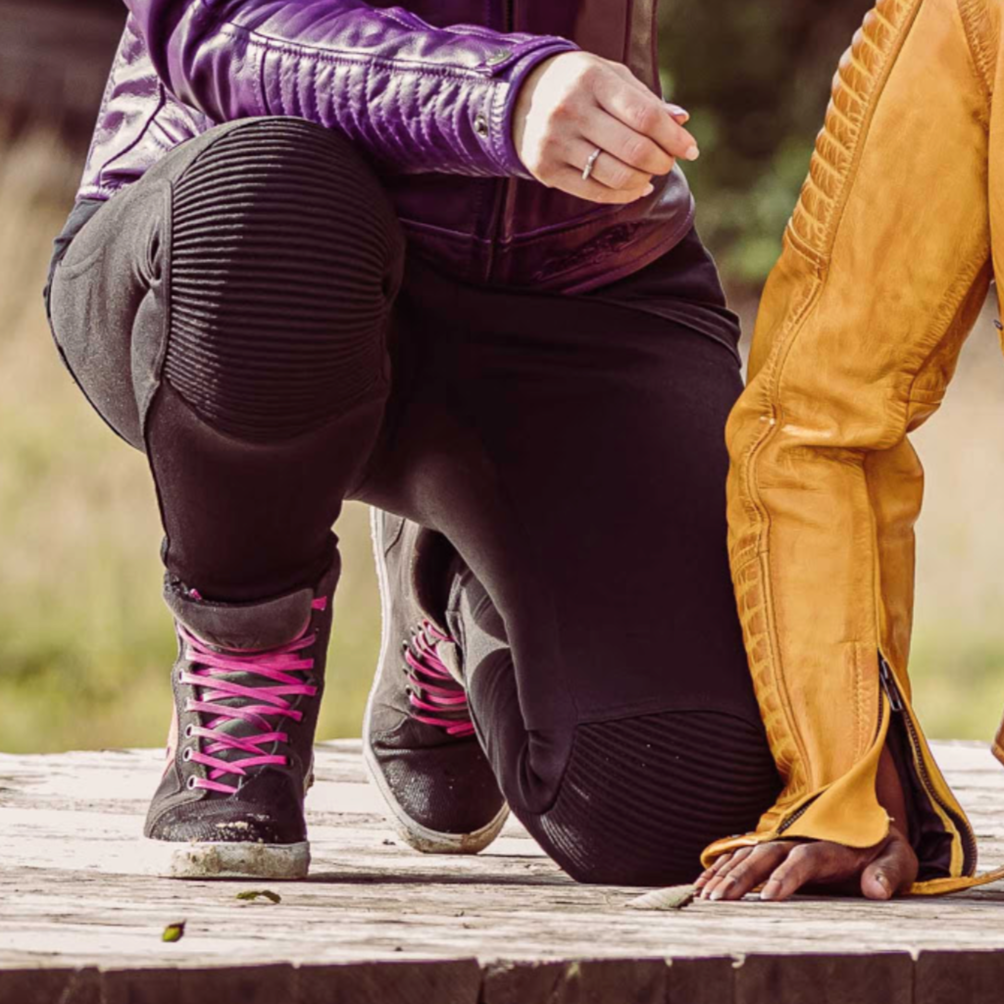 Close up of a woman&#39;s knee with black motorcycle leggings sherrie and Valerie purple jacket