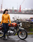 A woman with her motorcycle wearing yellow Valerie motorcycle leather jacket from MotoGirl