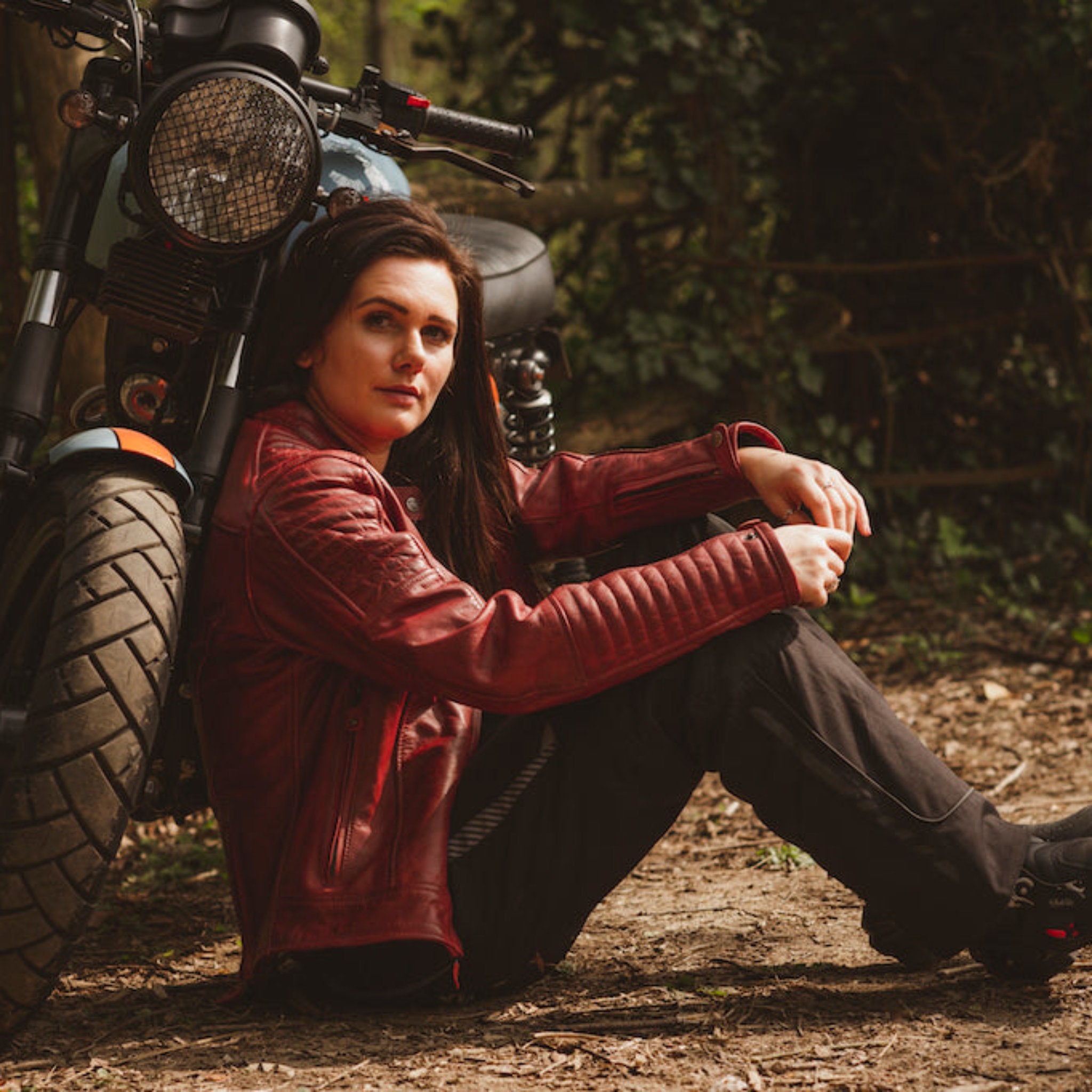 A woman with her motorcycle wearing red Valerie motorcycle leather jacket from Moto Girl