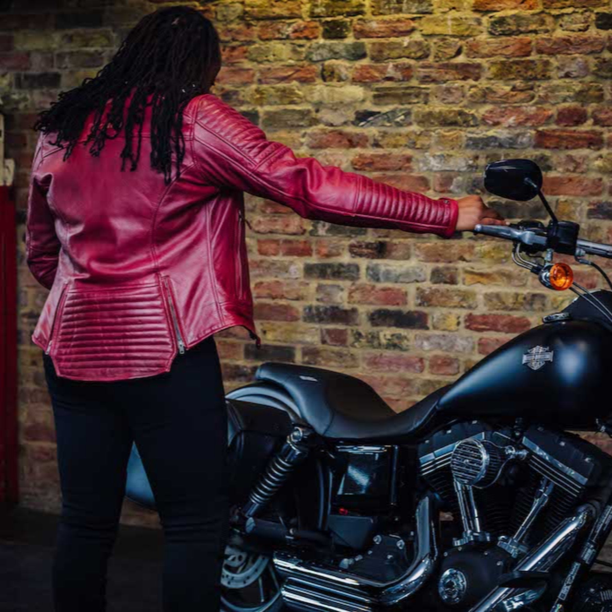 A woman with her motorcycle wearing red Valerie motorcycle leather jacket from MotoGirl